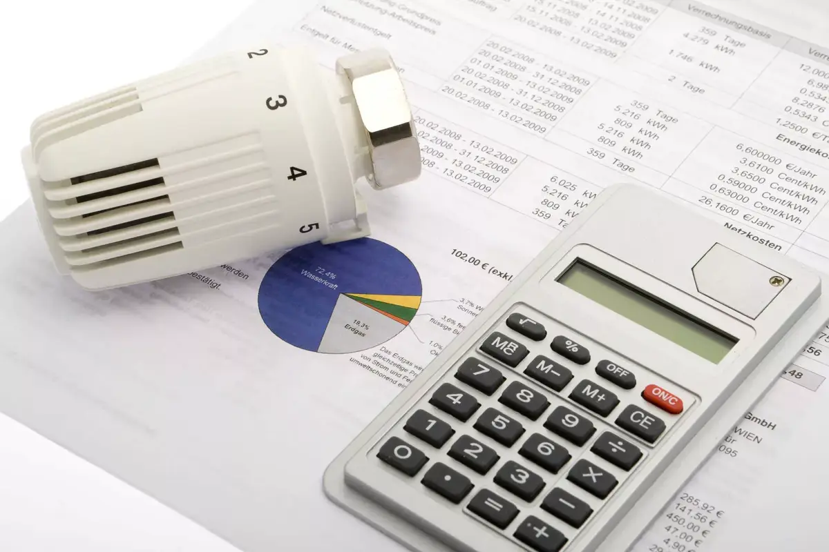Stromrechnung und Gasrechnung nebeneinander auf einem Schreibtisch mit deutlich sichtbaren Eurobetr&auml;gen, daneben ein Taschenrechner &ndash; Vergleich der Heizkosten 2026